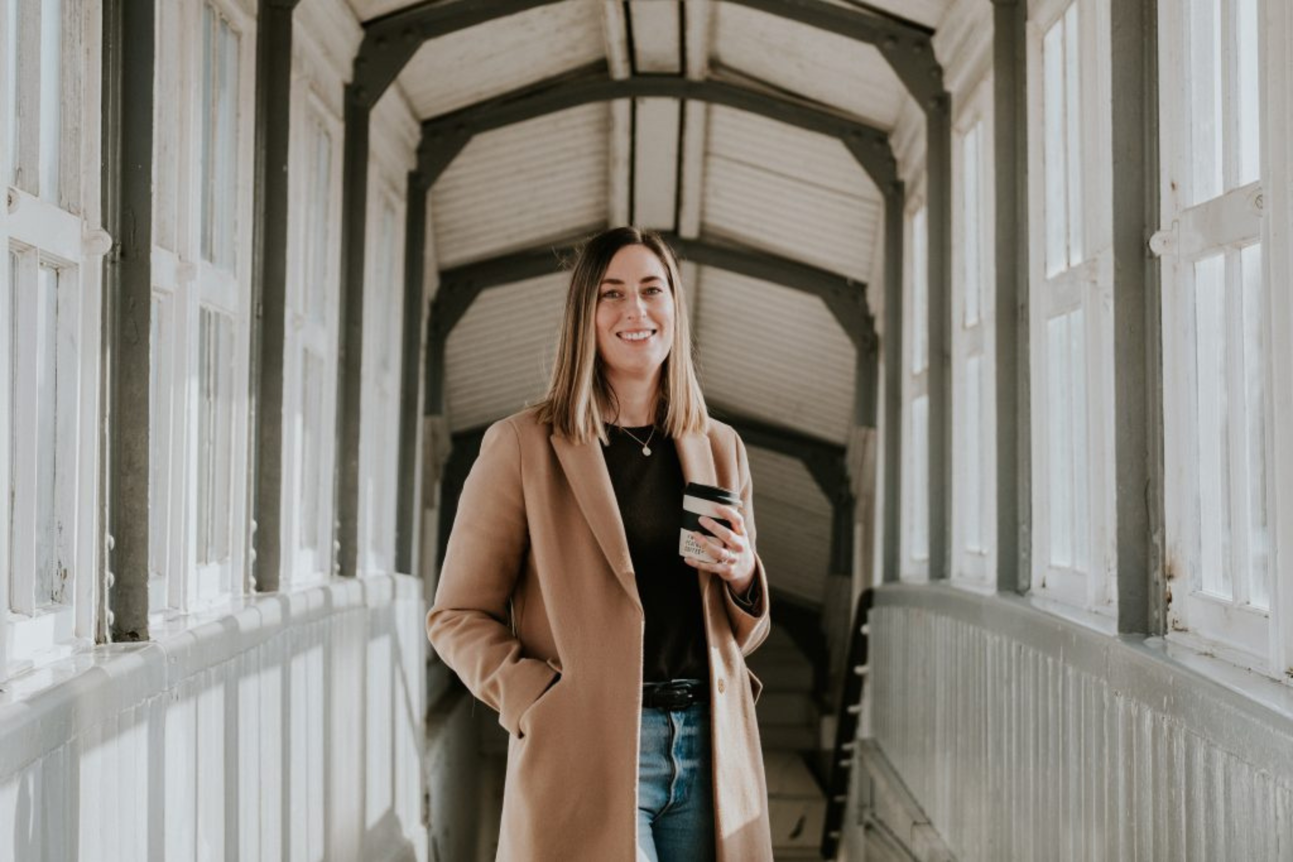 Holly Buckingham founder of White Feather Coffee Co. stood at the train station holding a coffee.